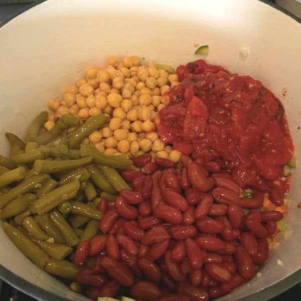 adding beans and tomatoes into soup