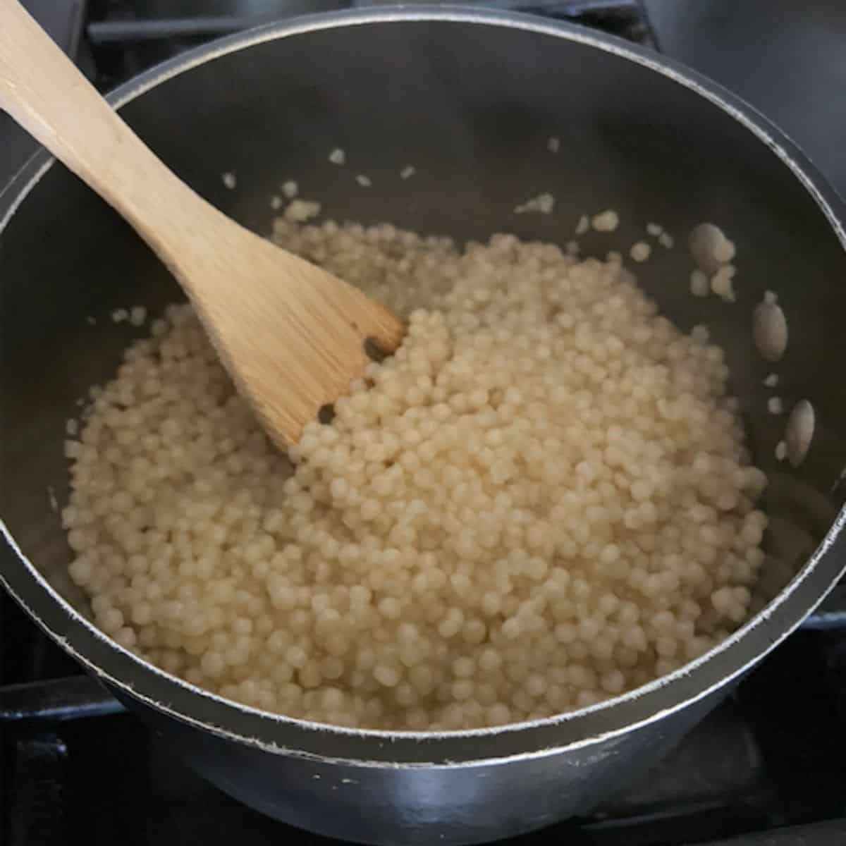 couscous in a pot with wooden spoon