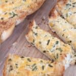 garlic cheesy bread sliced into pieces on cutting board