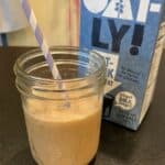 mason jar full of iced honey oat milk latte with oatly jug in background