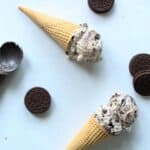 two sugar cones laying on gray background with oreo cookies around them