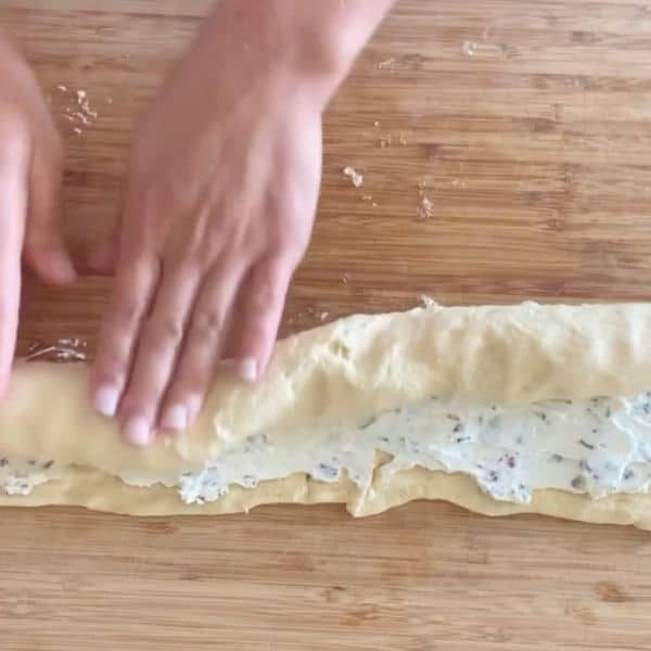 hands rolling the crescent dough into a log shape