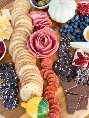 charcuterie board filled with fruit, crackers, meat, chocolate, cheese, etc.