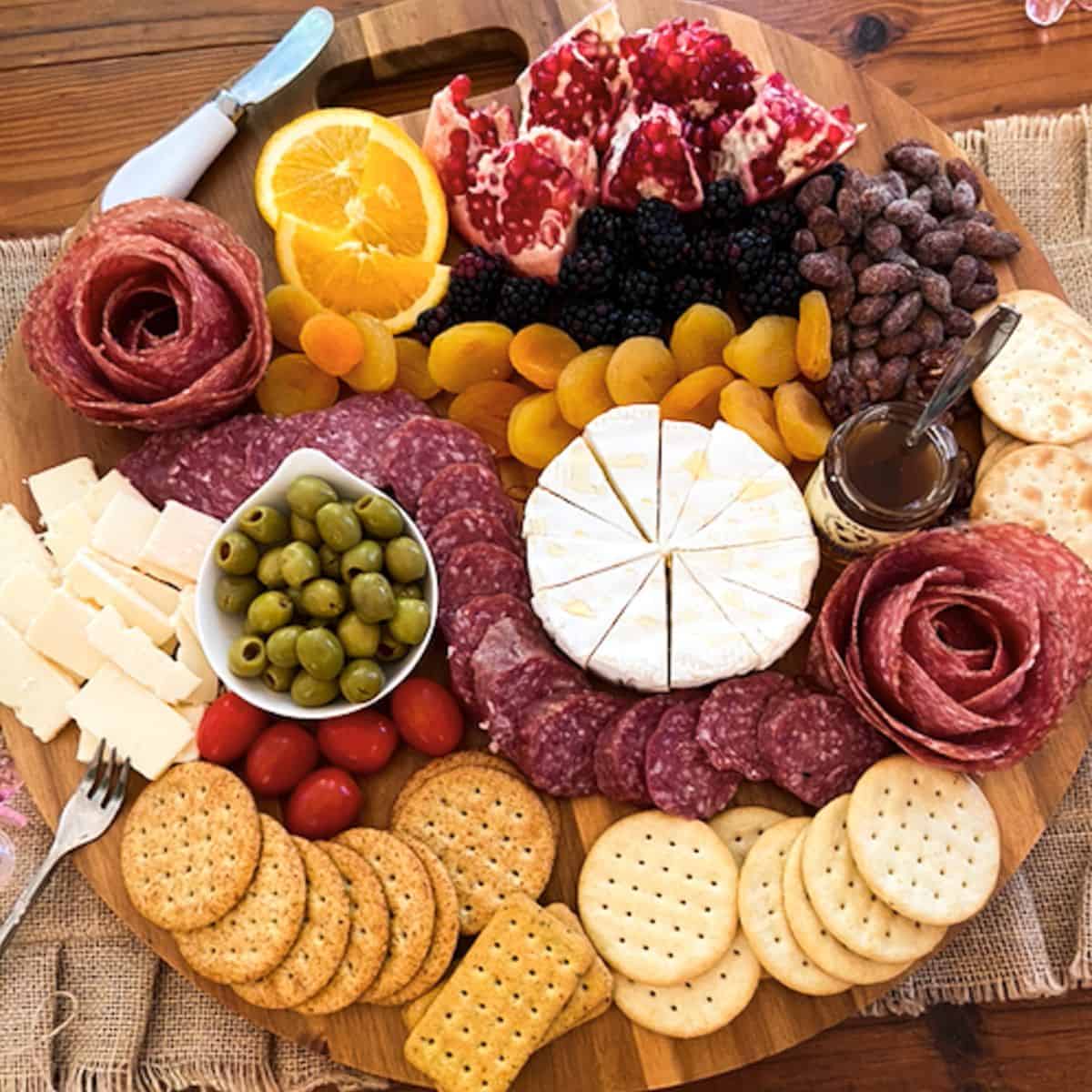 charcuterie board filled with fruit, crackers, meat, chocolate, cheese, etc.