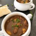 beef stew in bowl with french bread on table