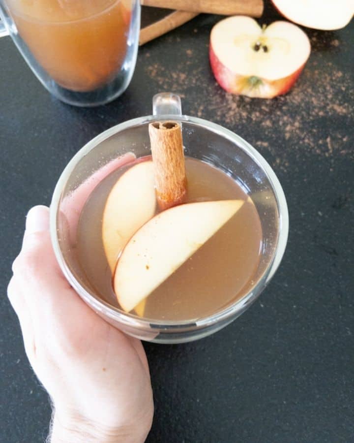 hand holding a warm bourbon apple cider mug