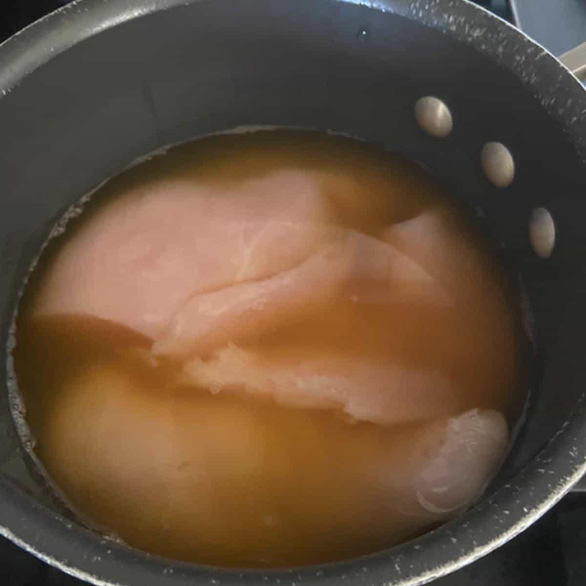 raw chicken in pot with chicken stock