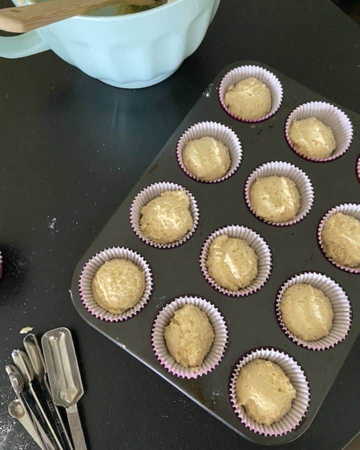 muffin tin full of corn bread muffin batter with measuring spoons on side