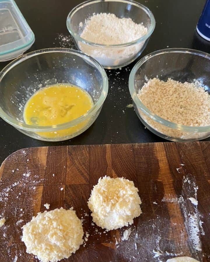 3 bowls of flour, egg, and panko with two goat cheese balls