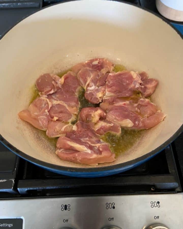 raw boneless chicken thighs cooking in dutch oven