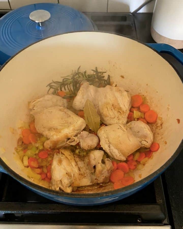 chicken thighs, vegetables and herbs in a dutch oven