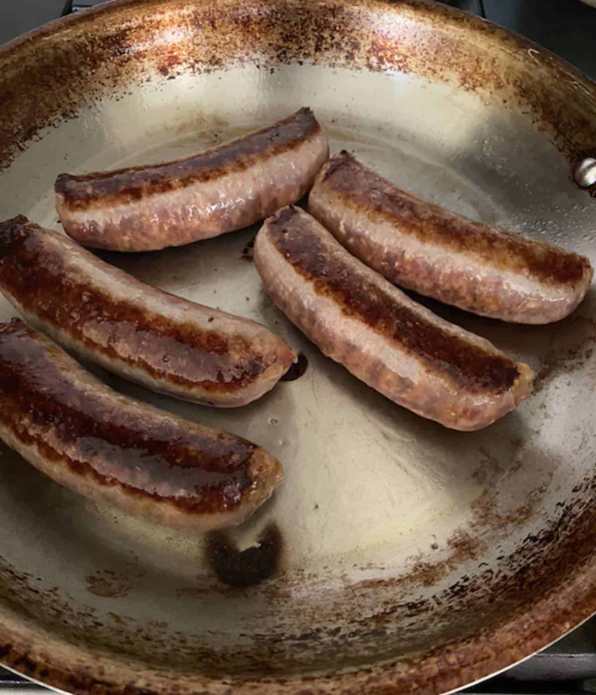 Sauteing sausages in pan.