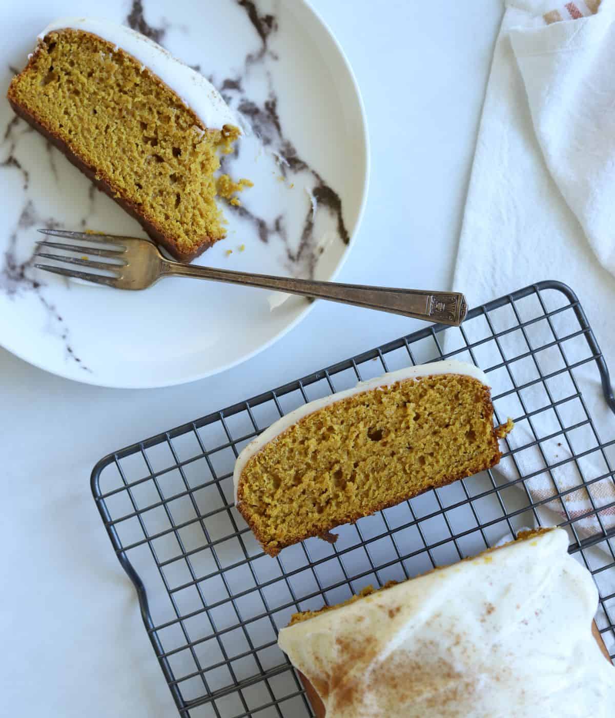 pumpkin bread sliced on a baking tray with a slice on a plate