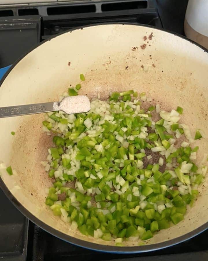 adding salt into veggie mixture in dutch oven
