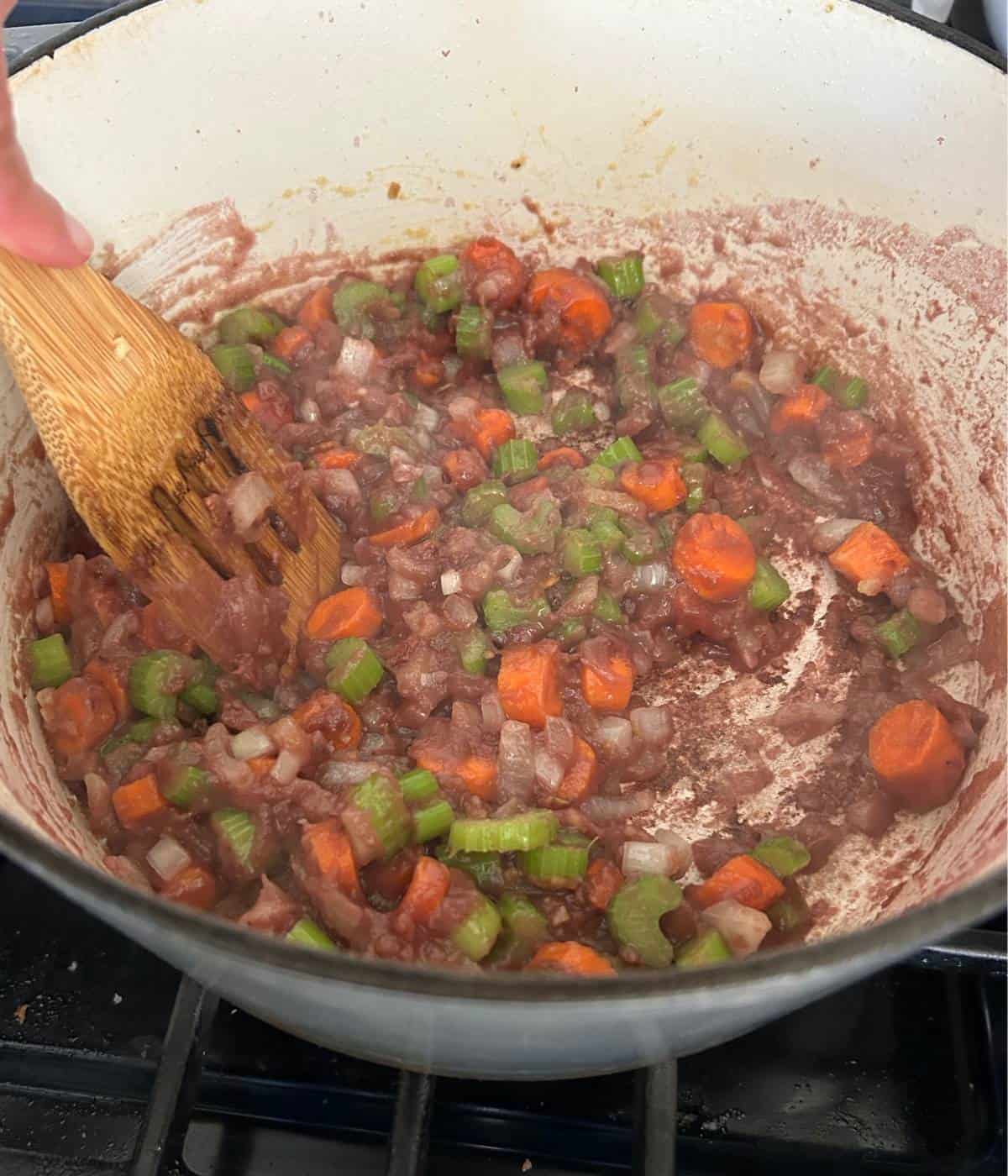 Vegetables with red wine in pot.