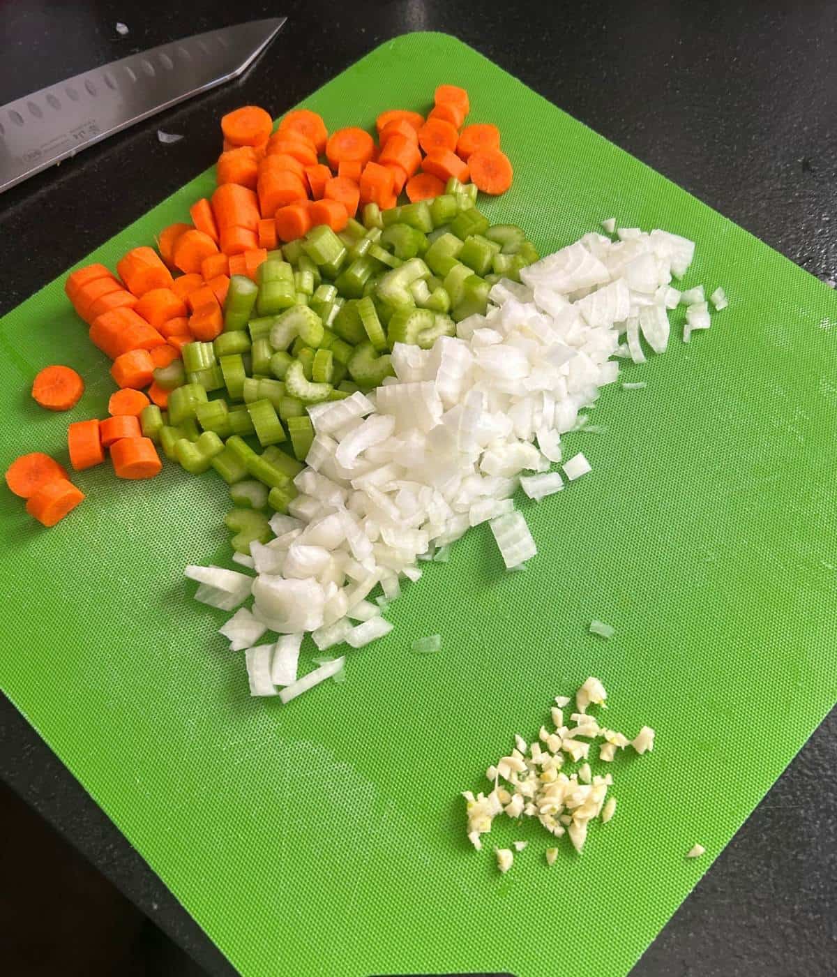 Vegetables for beef stew on cutting mat.