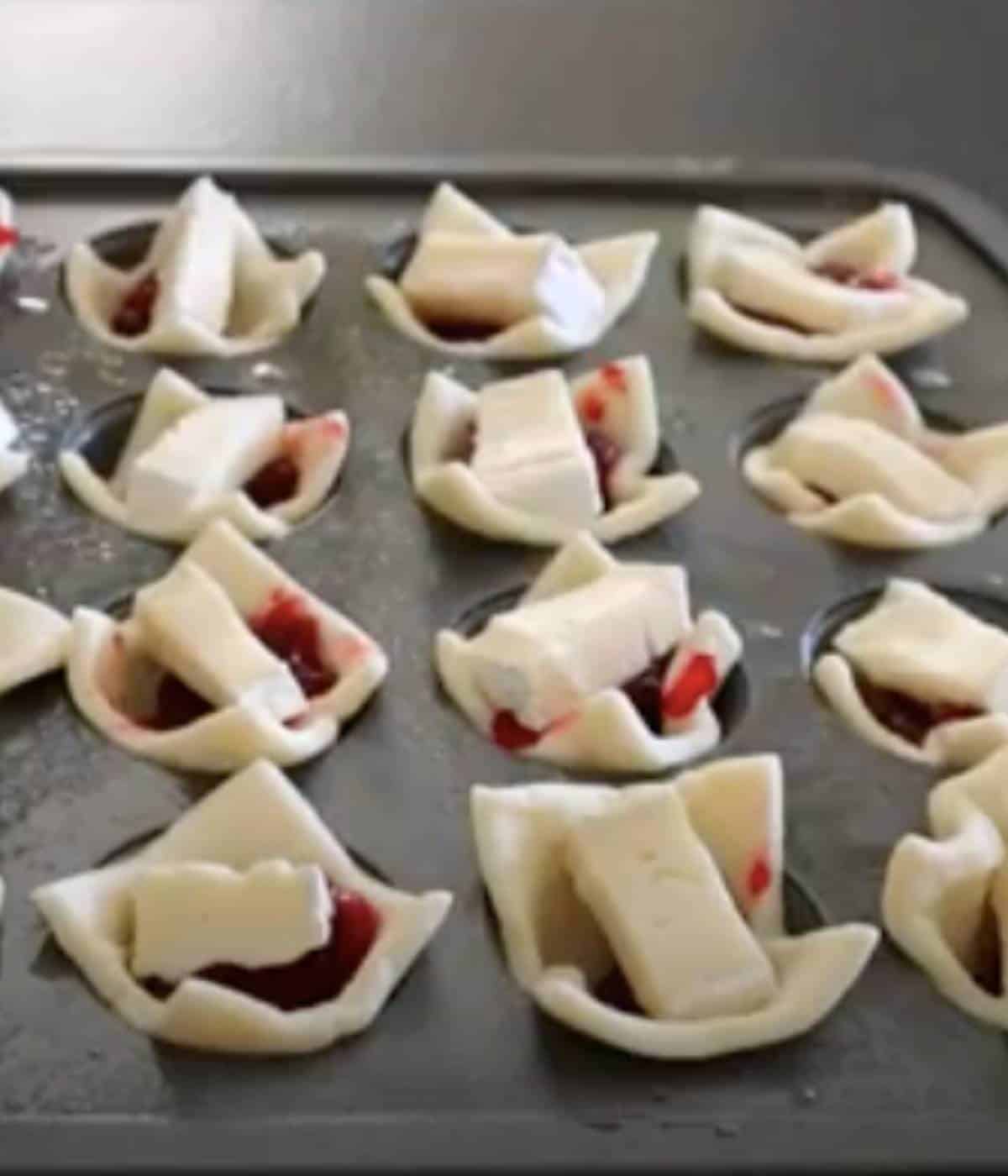 Puff pastry bites stuffed with brie and cranberries in mini muffin tin.