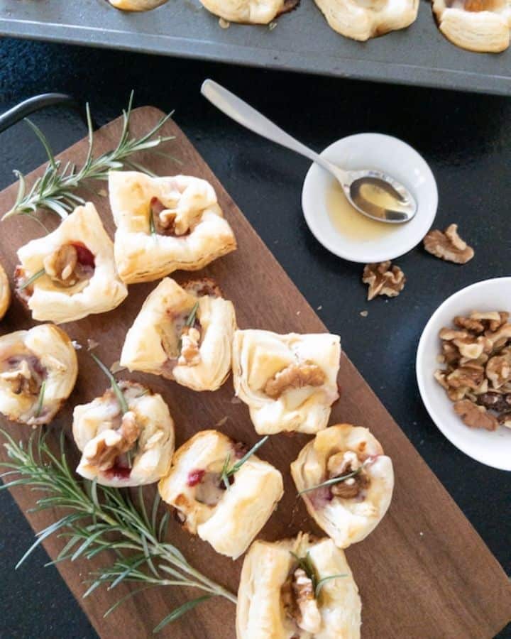 cranberry brie bites on wooden platter with side of honey and walnuts
