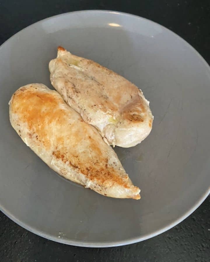 two chicken breasts cooked on gray plate
