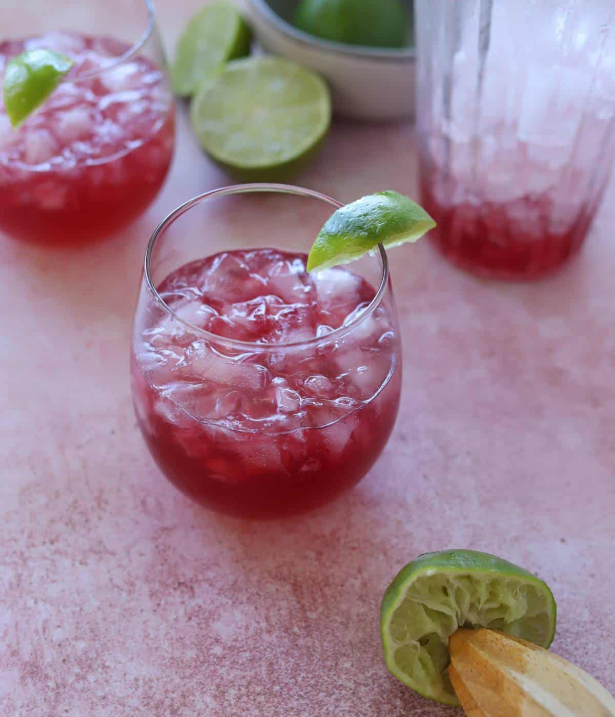 Pomegranate vodka cocktail in wine glass with a lime wedge.