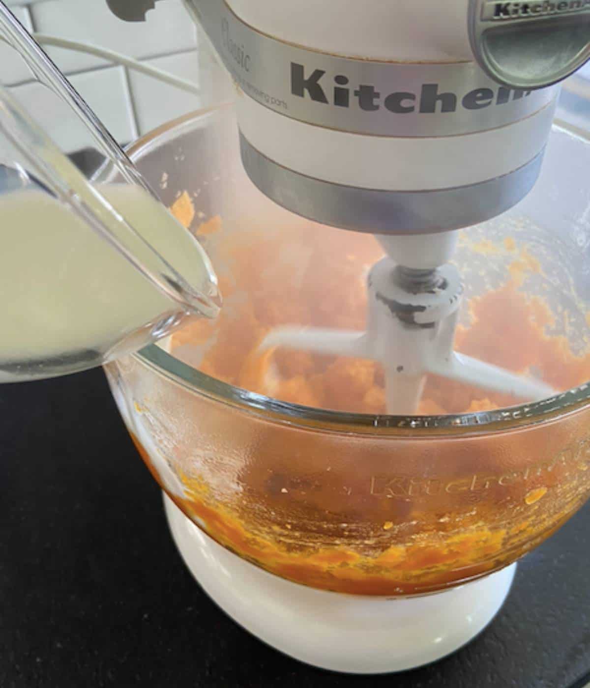 Pouring milk into sweet potatoes in stand mixer.
