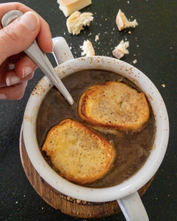 french onion soup topped with french bread and gruyere cheese in bowl with spoon