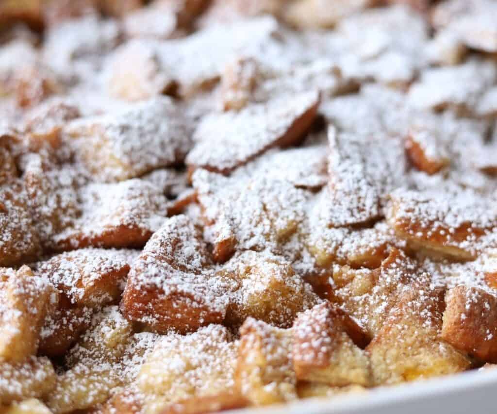 close up of brioche french toast casserole coated in powdered sugar