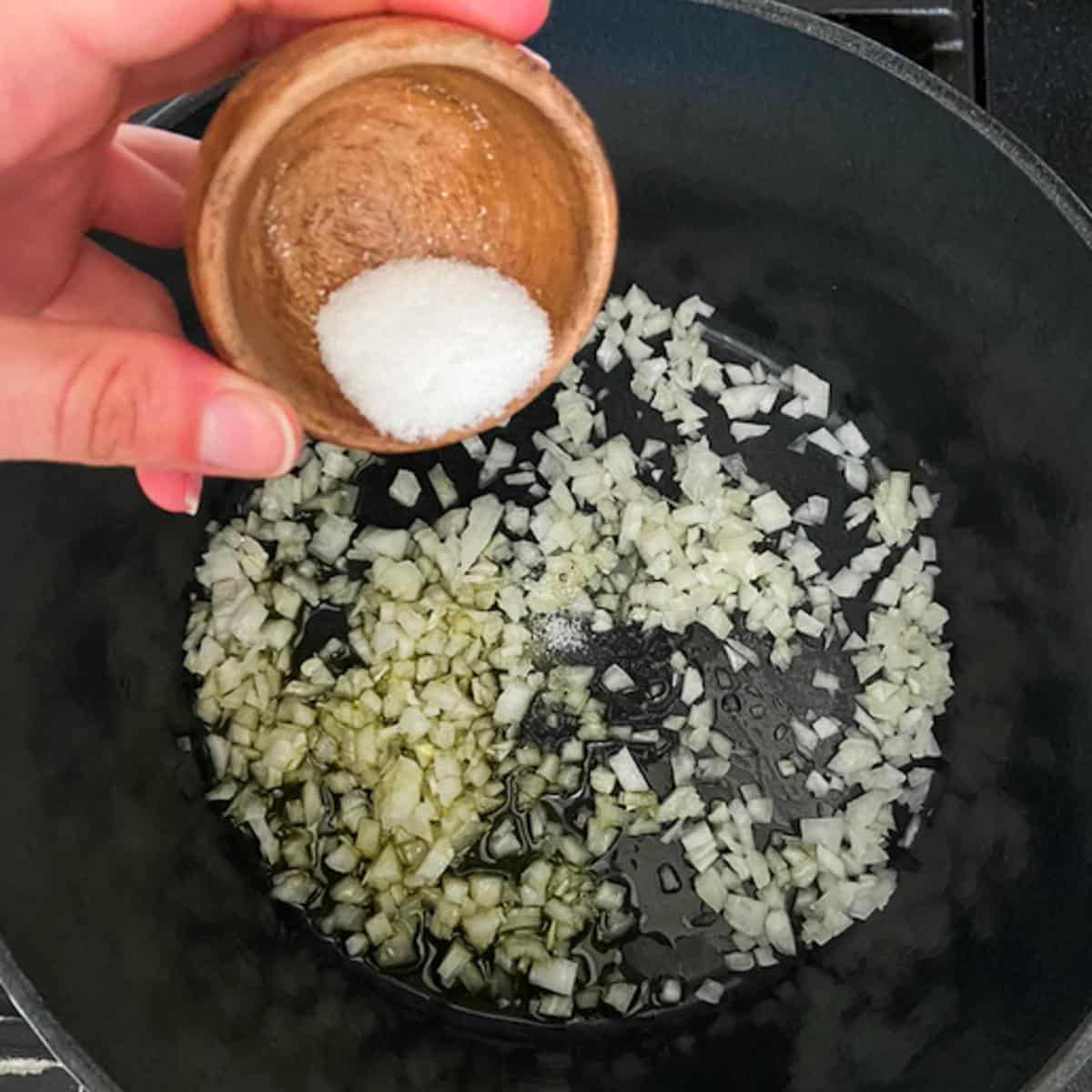 adding salt to onions in dutch oven