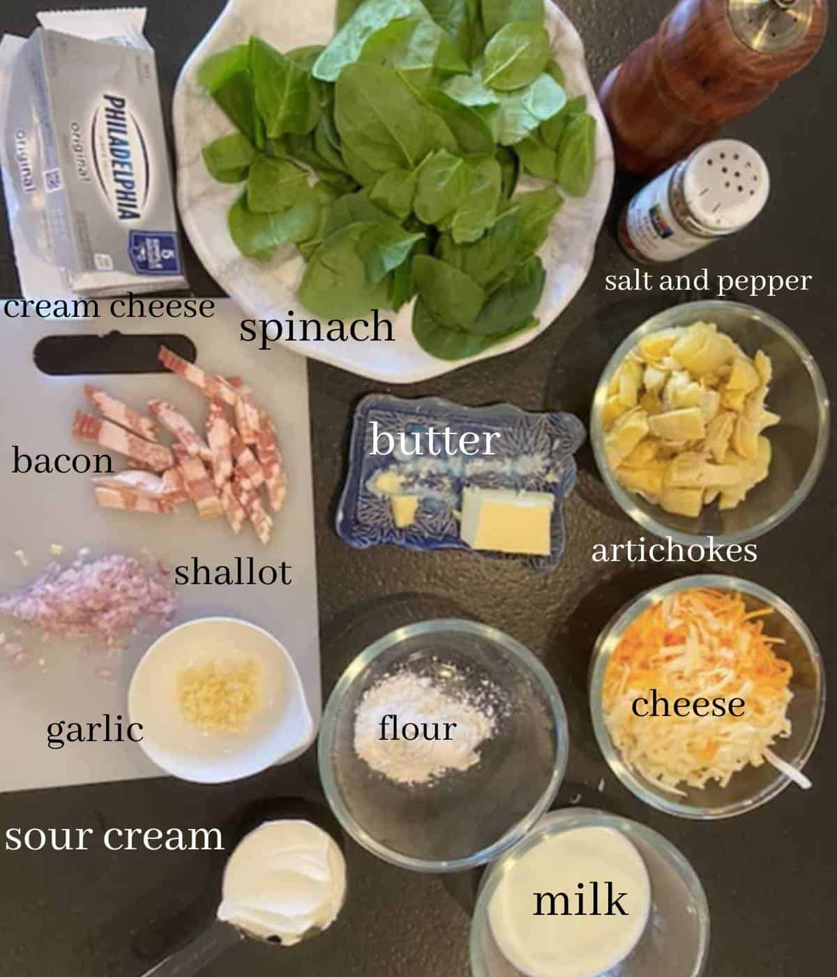Ingredients for spinach artichoke dip on black countertop. 