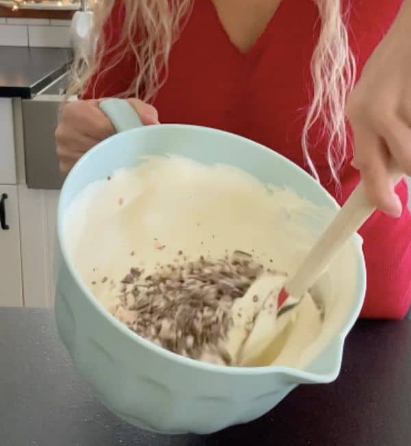 mixing in peppermint bark with spatula