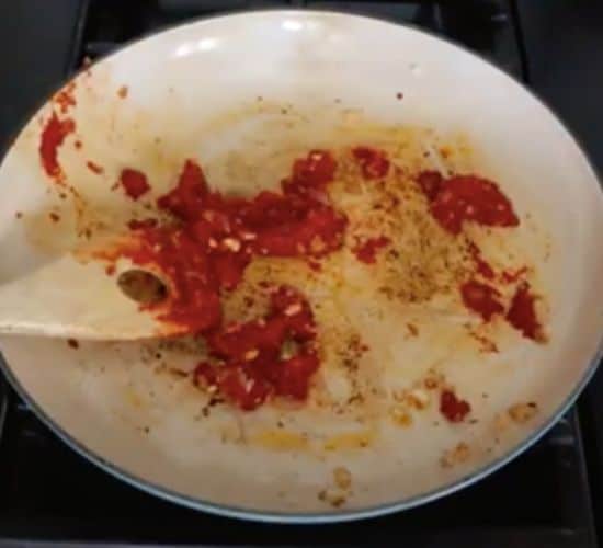 adding tomato paste into a skillet