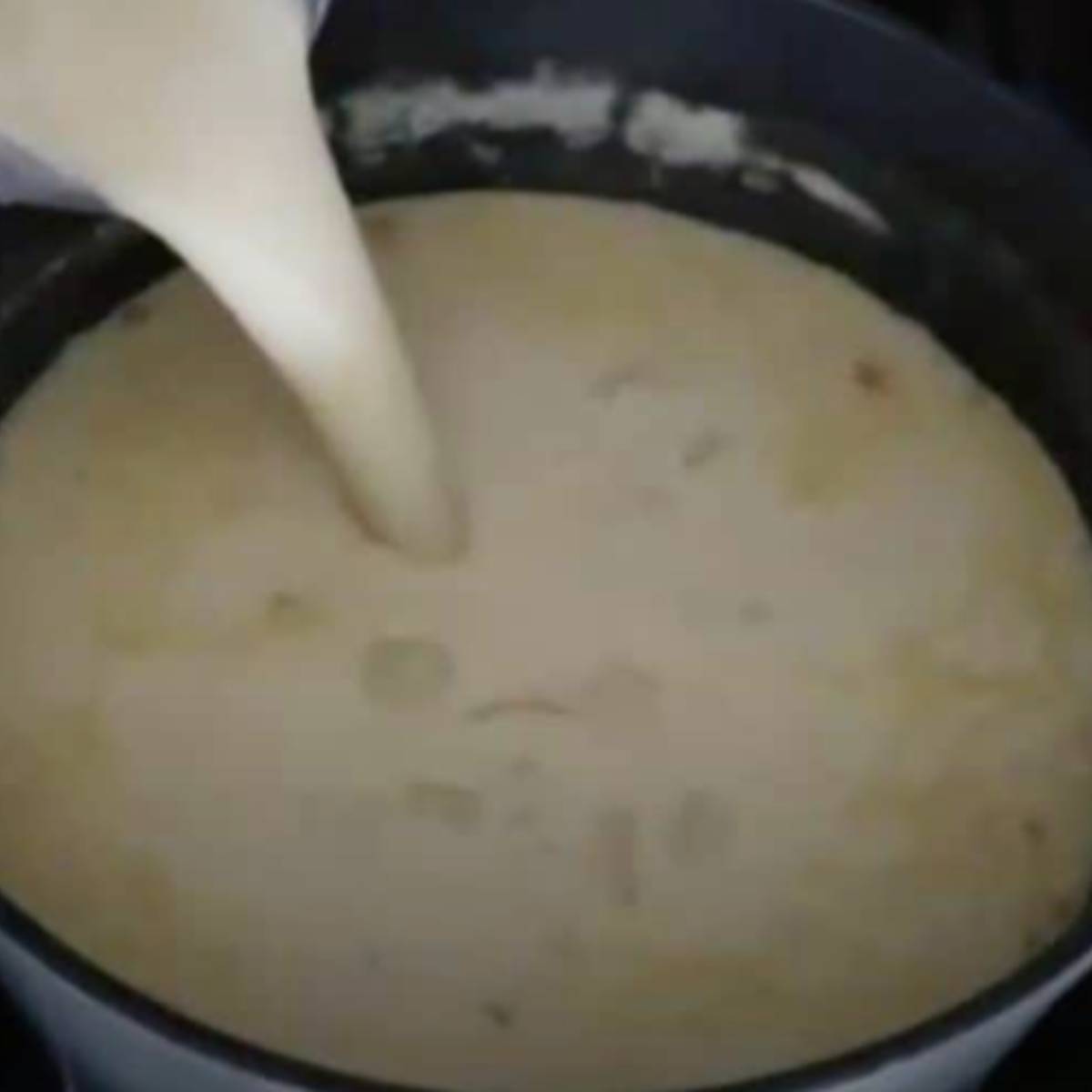 Pouring blended soup into potato soup.