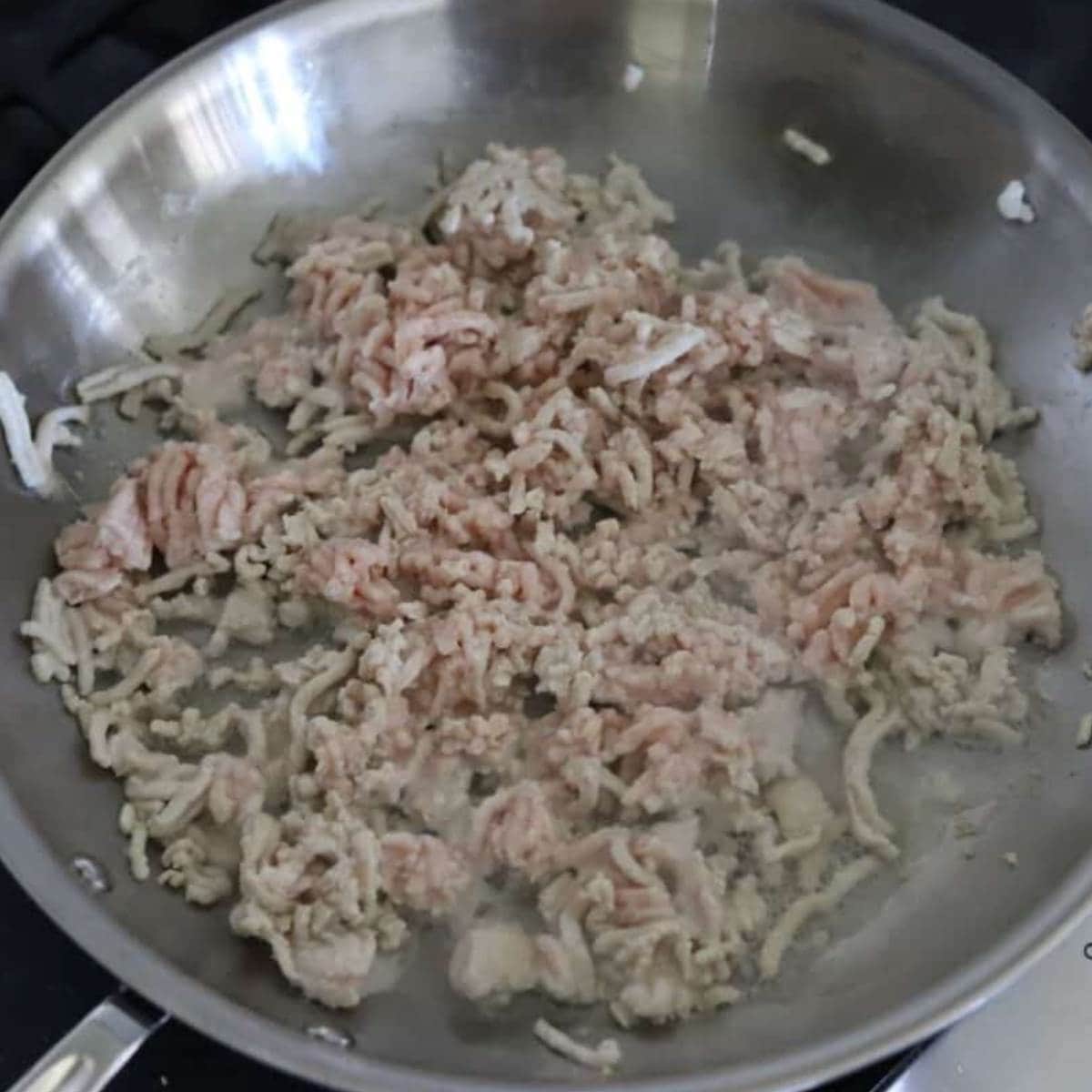 Ground chicken cooking in pan.