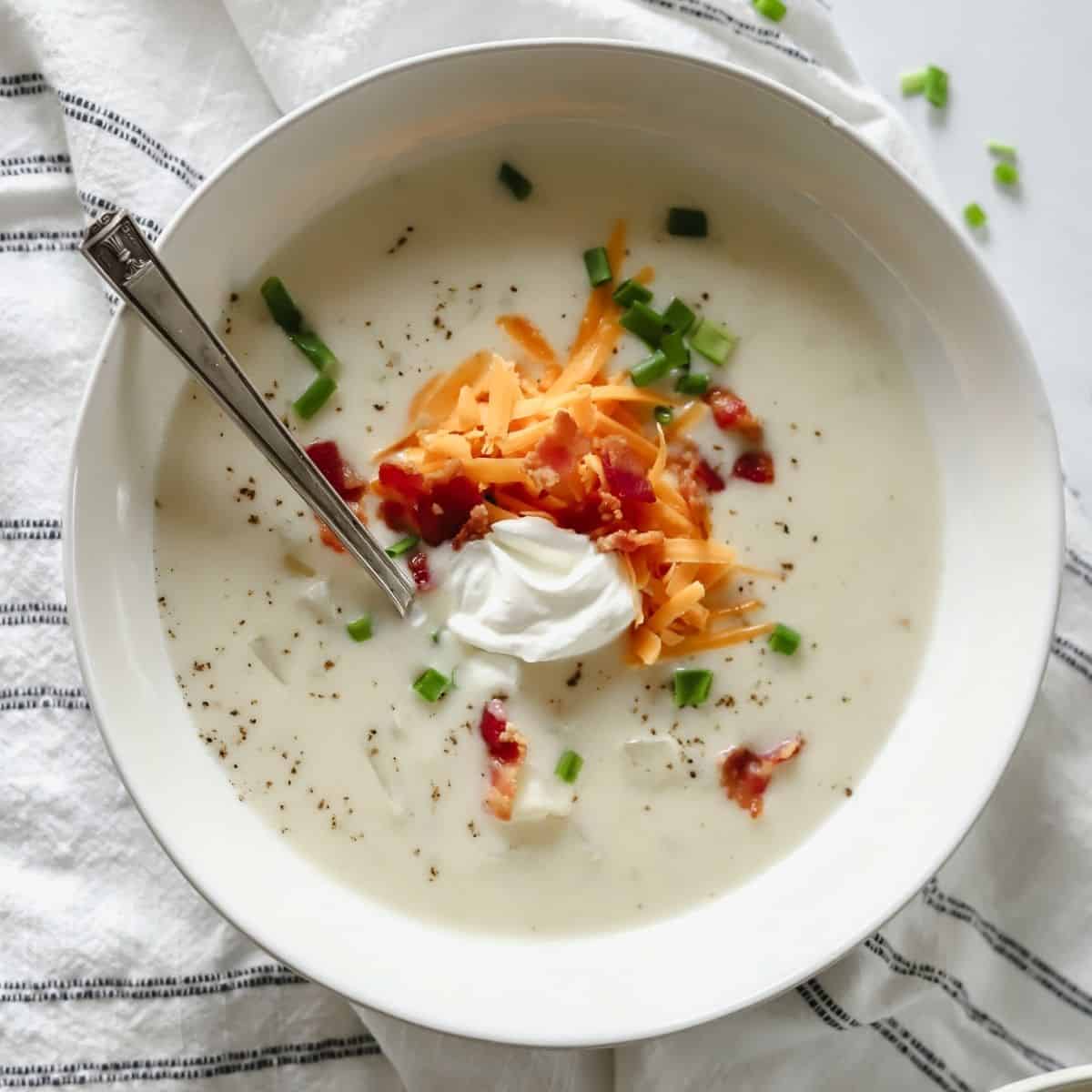 bowl of loaded baked potato soup topped with cheese, sour cream, bacon and chives