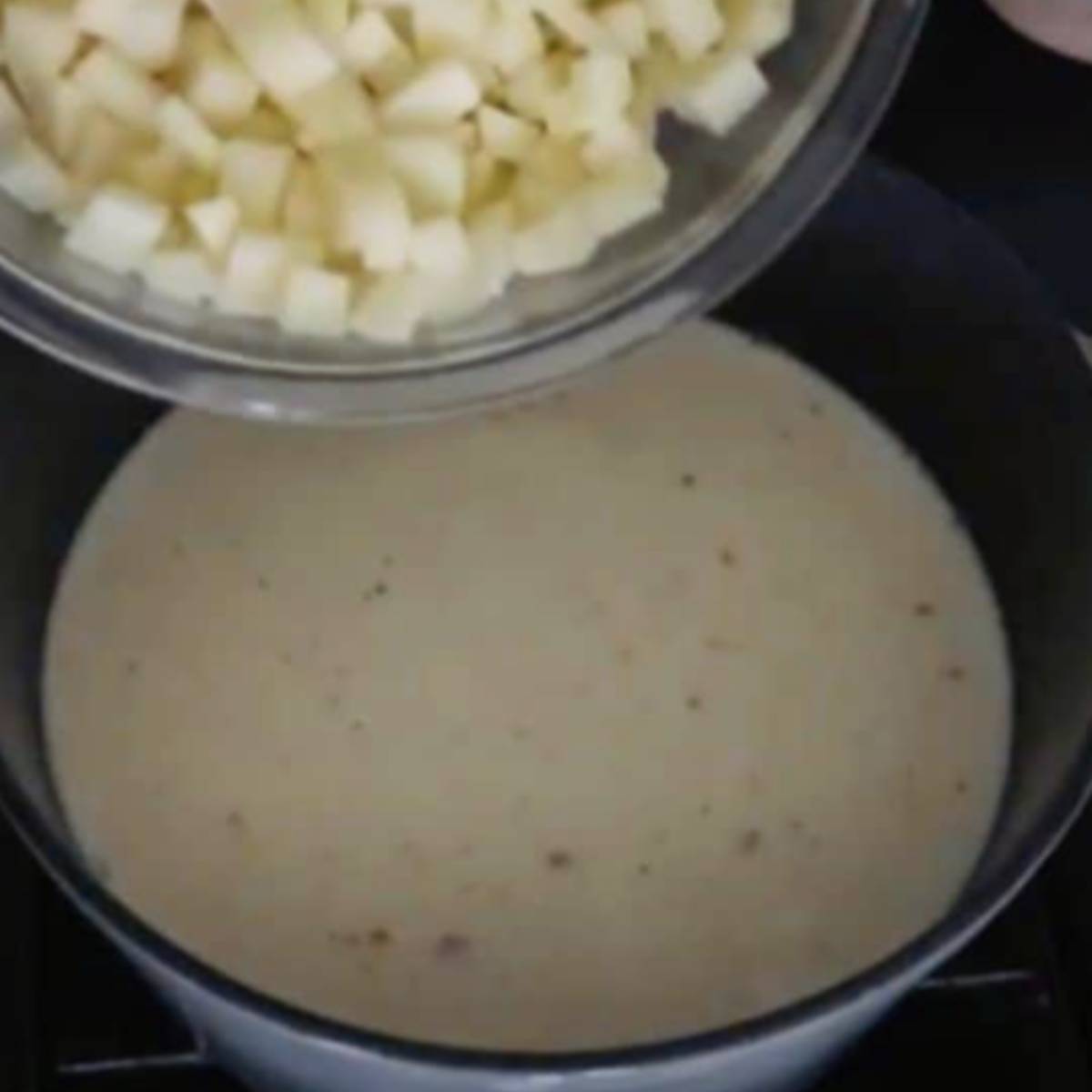 Potatoes pouring into soup.