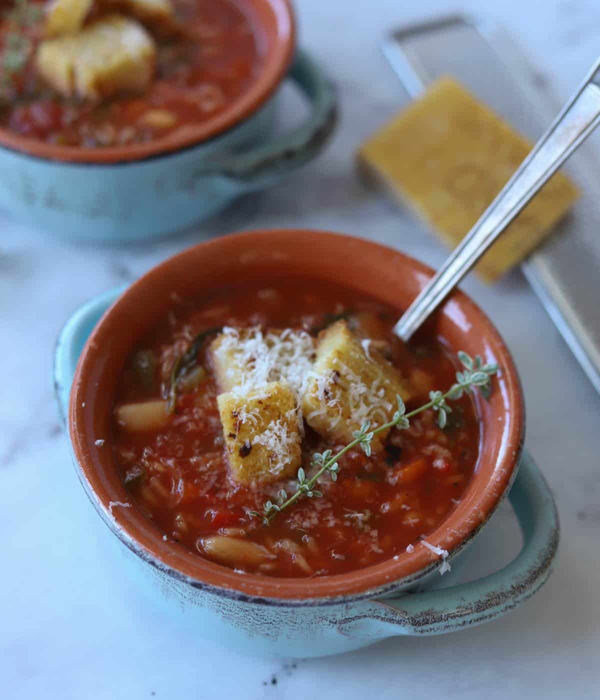 Vegetable soup in blue bowl topped with cheese and soup croutons.
