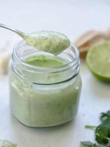 avocado cream sauce in jar with a spoon holding a serving