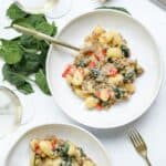 Large bowl filled with creamy italian sausage spinach gnocchi with a gold fork