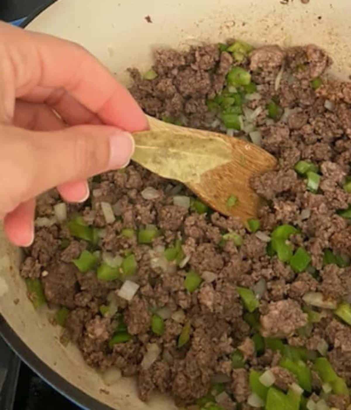Hand adding bay leaf to soup.