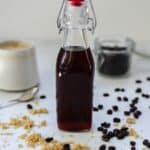 bottle of brown sugar simple syrup with coffee and coffee beans in the background