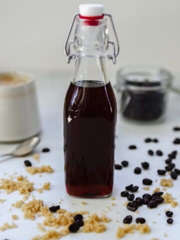 bottle of brown sugar simple syrup with coffee and coffee beans in the background