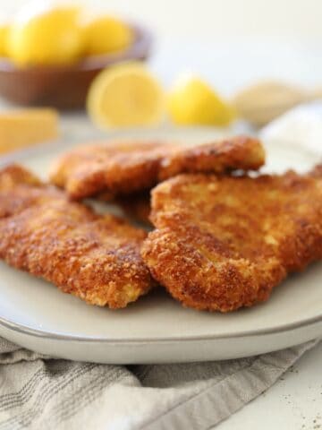 crispy chicken fritter on a plate with lemons and parmesan cheese in the background