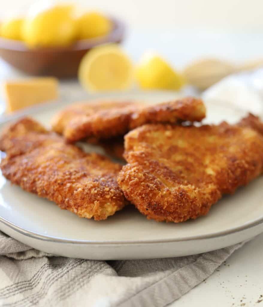 crispy chicken fritter on a plate with lemons and parmesan cheese in the background