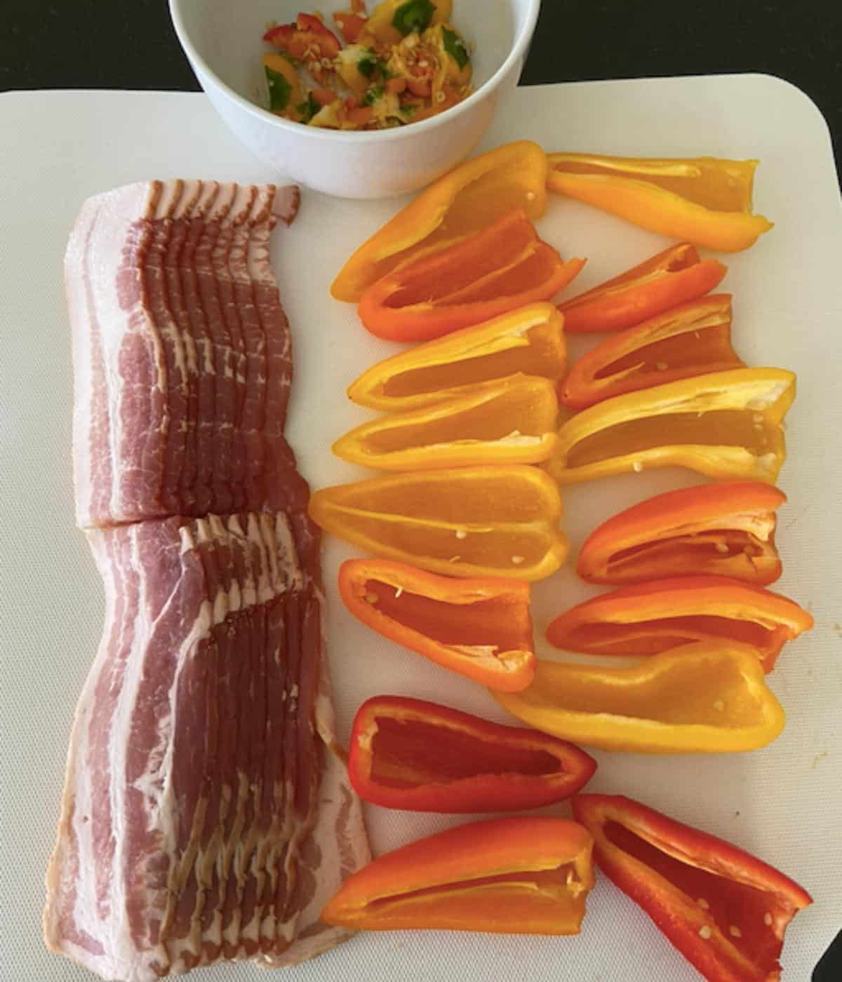 peppers with stems and seeds removed and bacon cut in half on cutting board