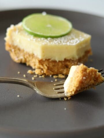 key lime pie bar on gray plate with a fork holding a bite of the dessert