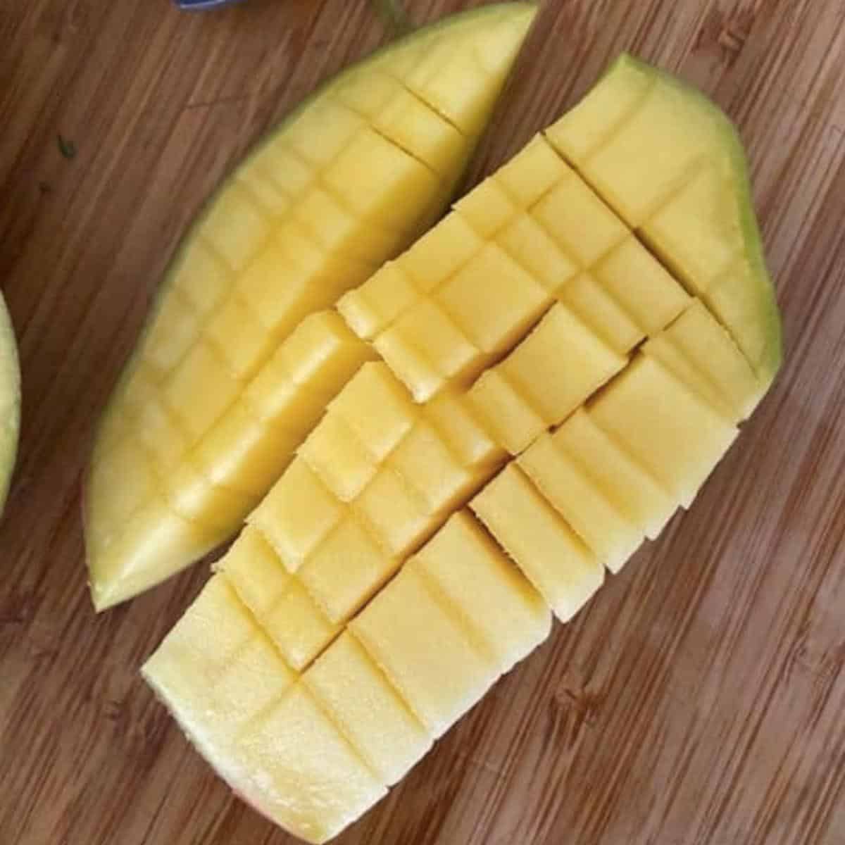 Mango cut with gridlines on cutting board.
