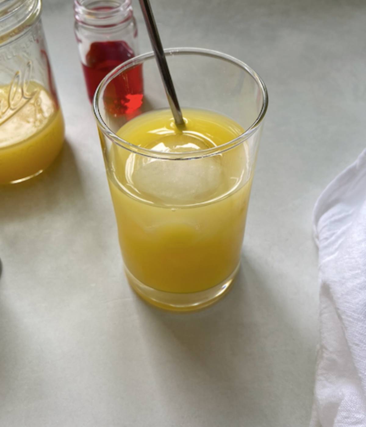 Orange juice and vodka in a glass with ice and spoon.