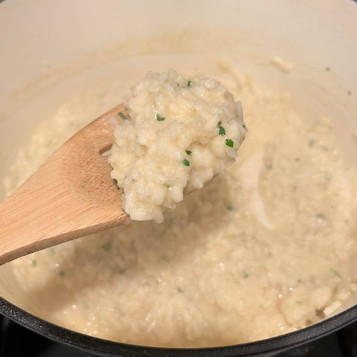 Wooden spoon showing texture of finished risotto.