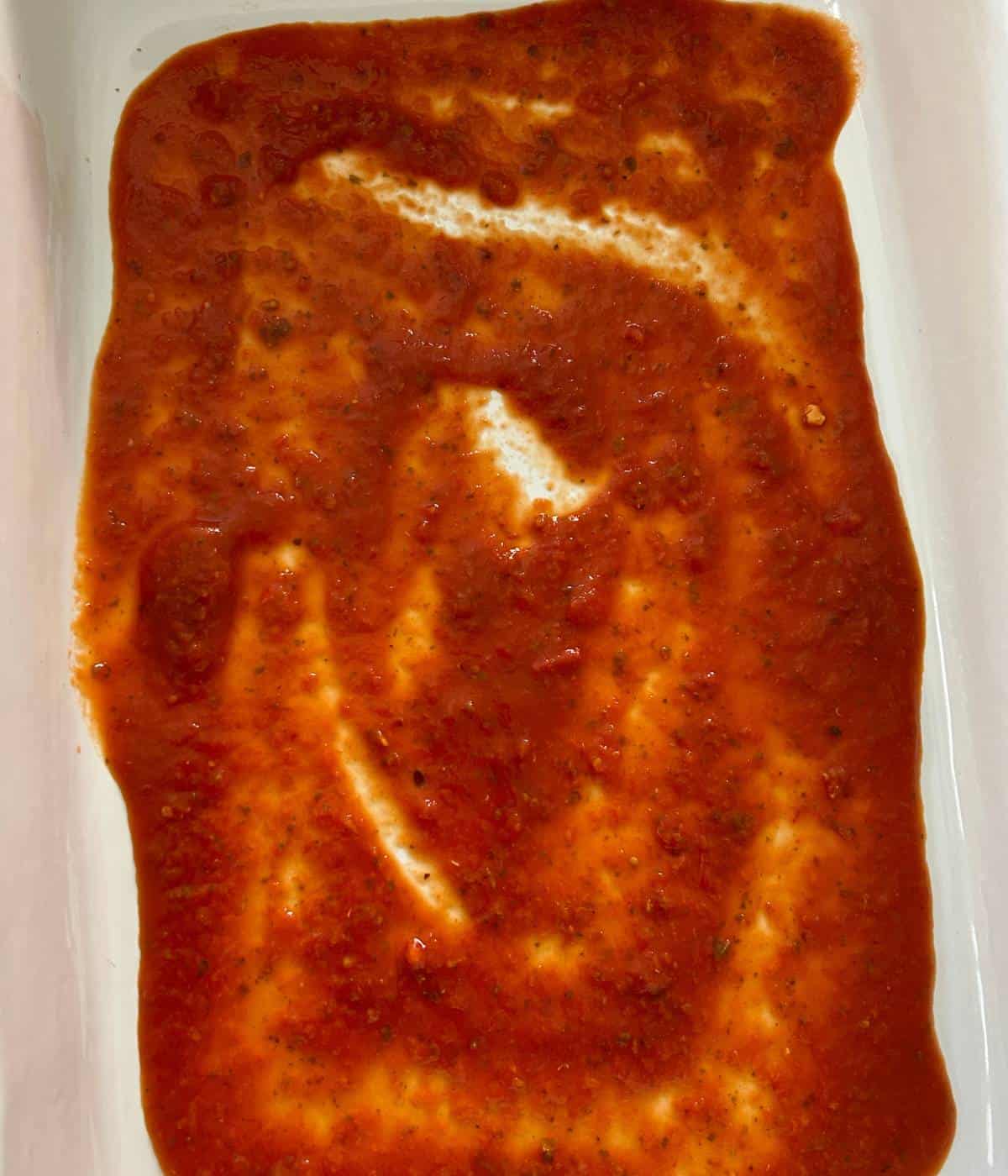 Sauce spread out in casserole dish.