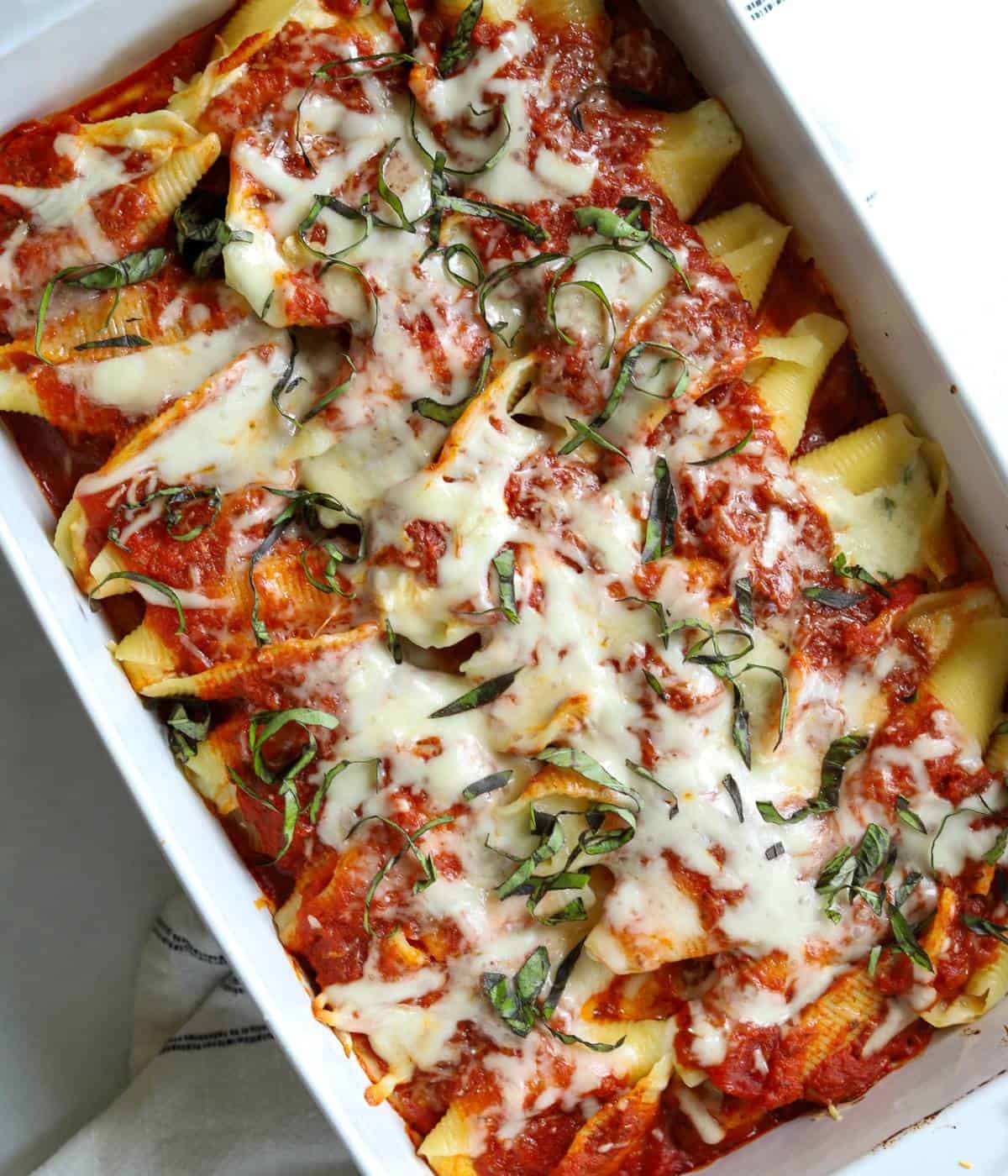 Stuffed shells topped with cheese, sauce, and basil.